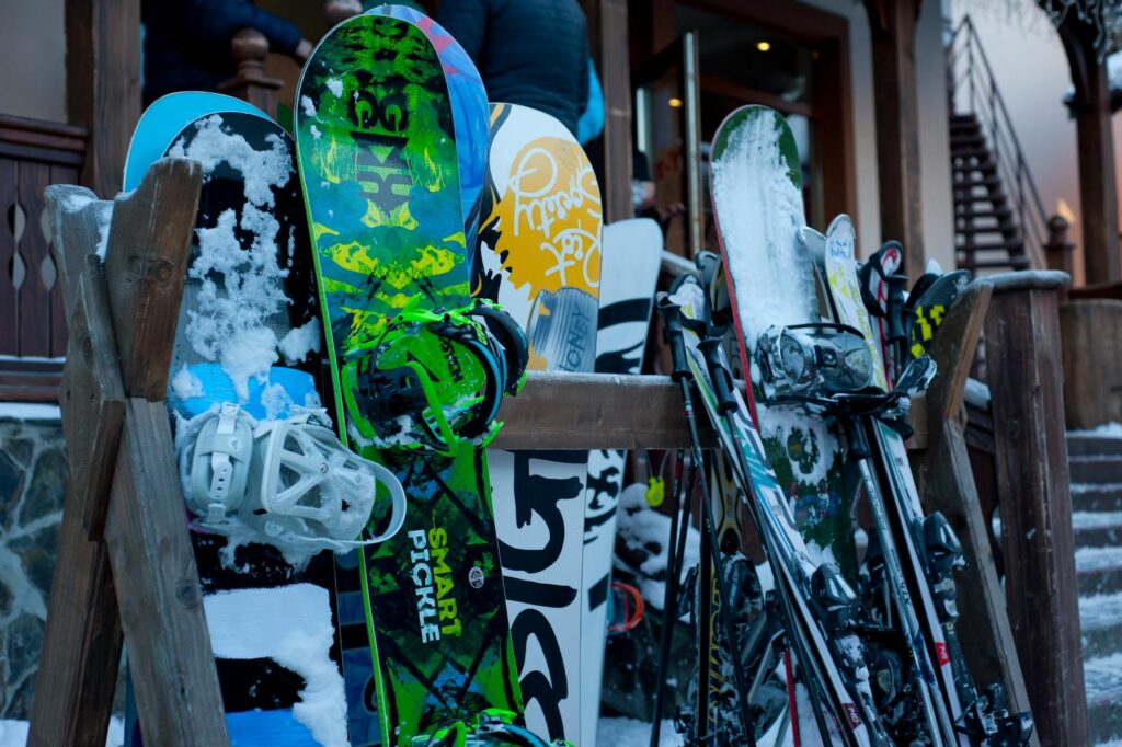 Snowboards and skis lined up outdoors at a winter ski lodge, showcasing vibrant designs.