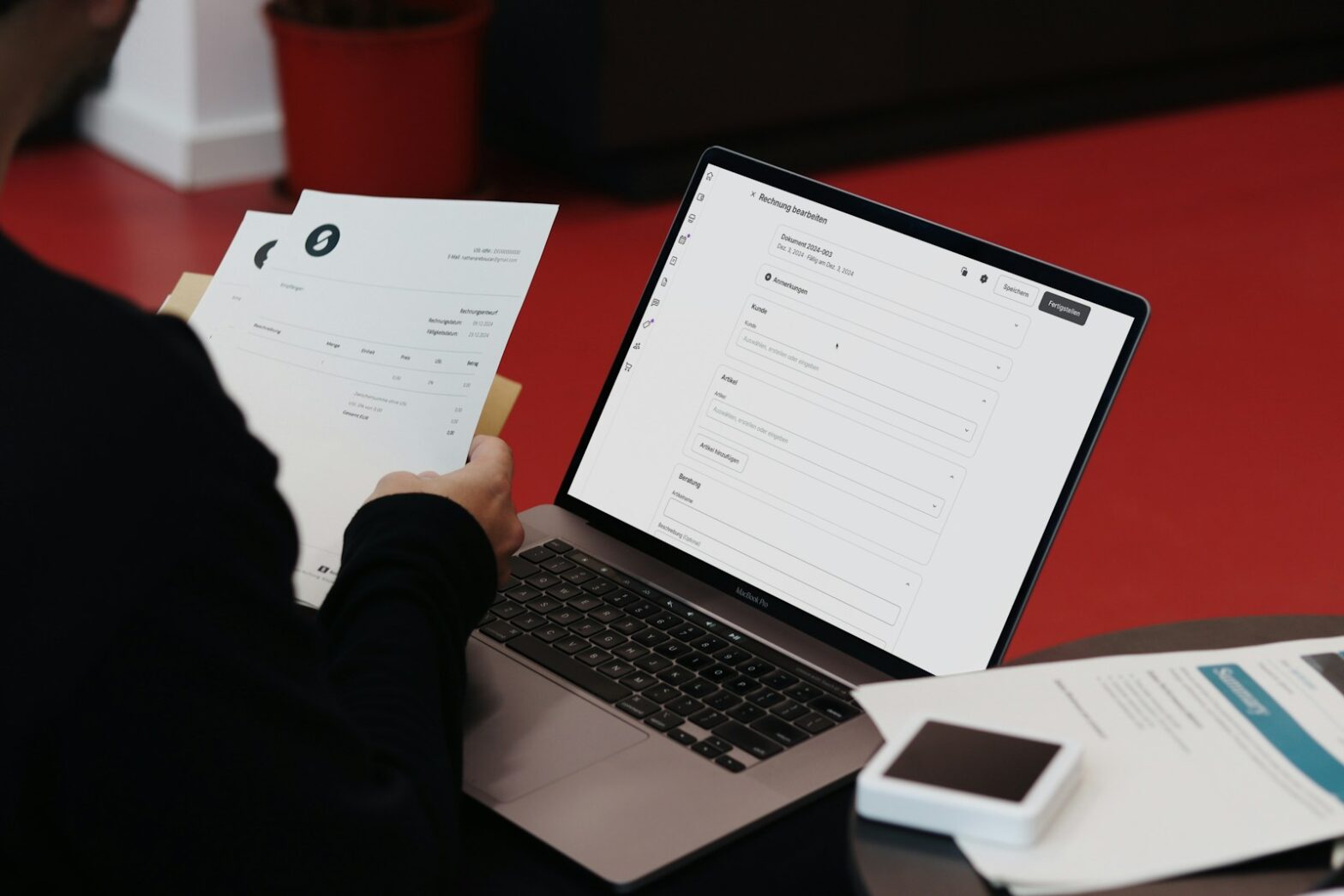 A person sitting at a desk with a laptop and papers